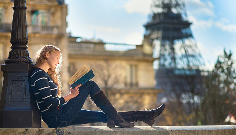 ragazza che legge con sfondo la torre eiffel