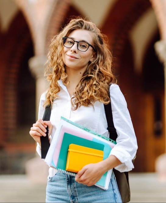 ragazza sorridente con occhiali e libri in mano
