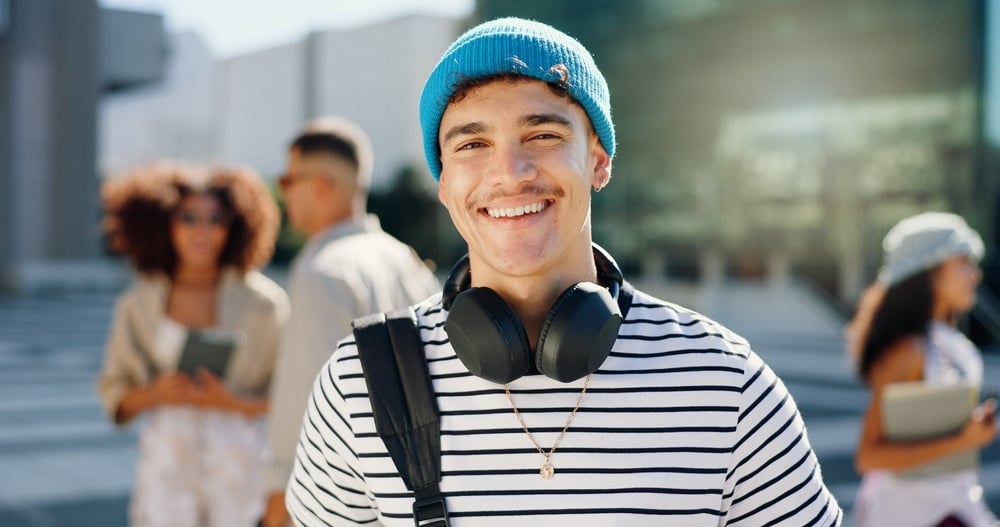 ragazzo sorridente, con berretto celeste e cuffie al collo